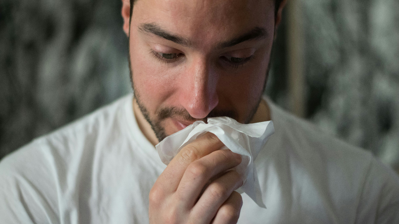 man wiping nose with tissue