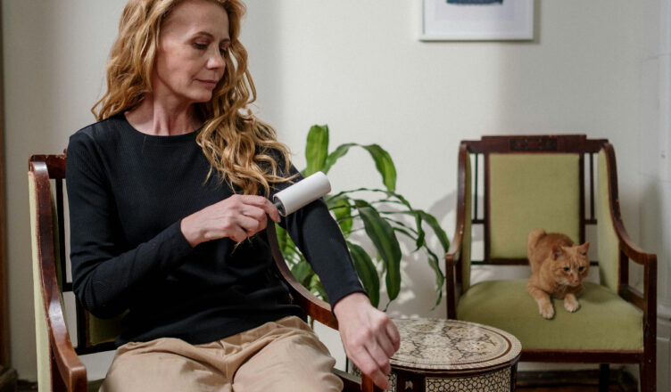 woman with lint roller and cat