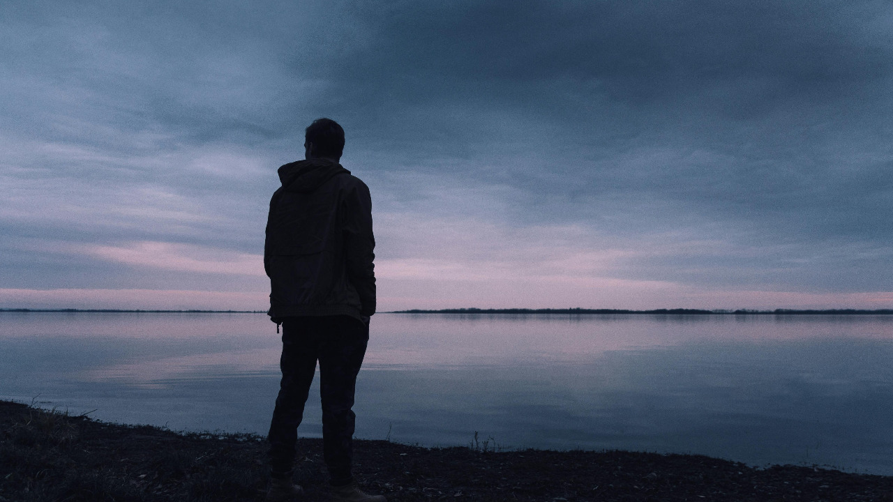 man silhouette against lake and sky background