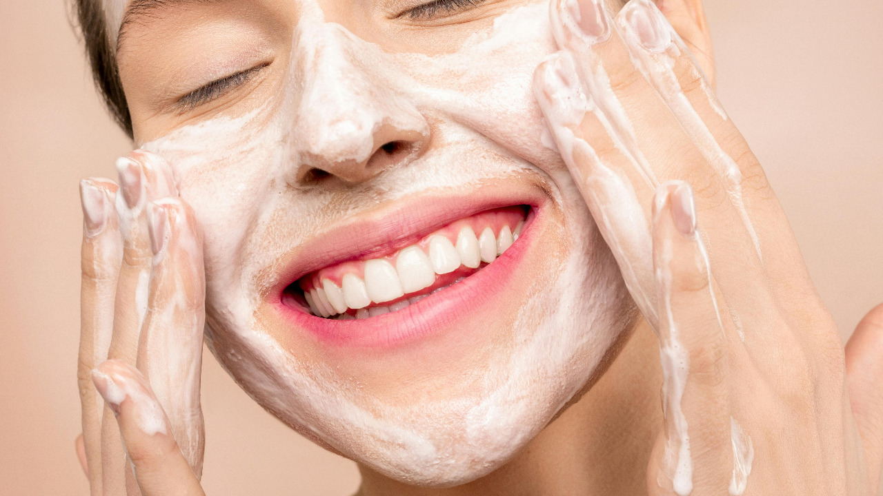 smiling girl putting lotion on face