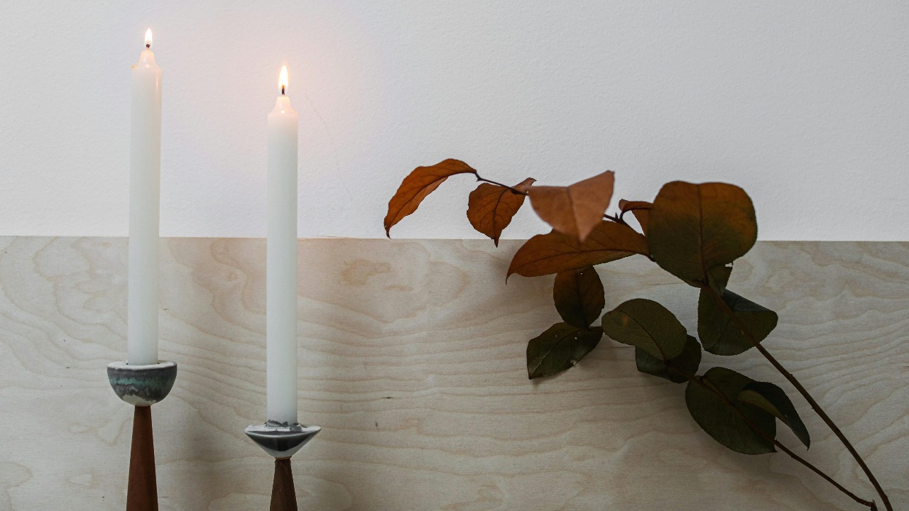 two candles with dried leaves